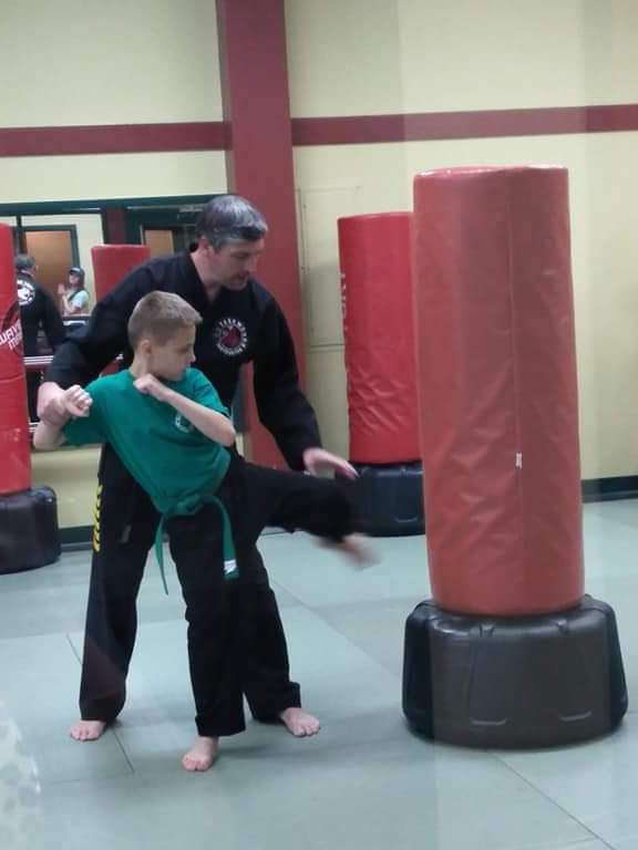 Master Graham coaching a green belt student through a side kick